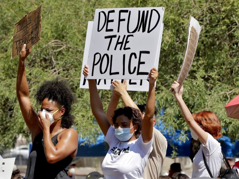 protesters hold up Defund the police sign – AP
